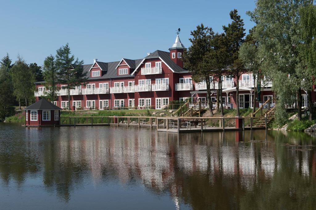 ein großes rotes Gebäude neben einem Gewässer in der Unterkunft Hotel Fårup in Blokhus