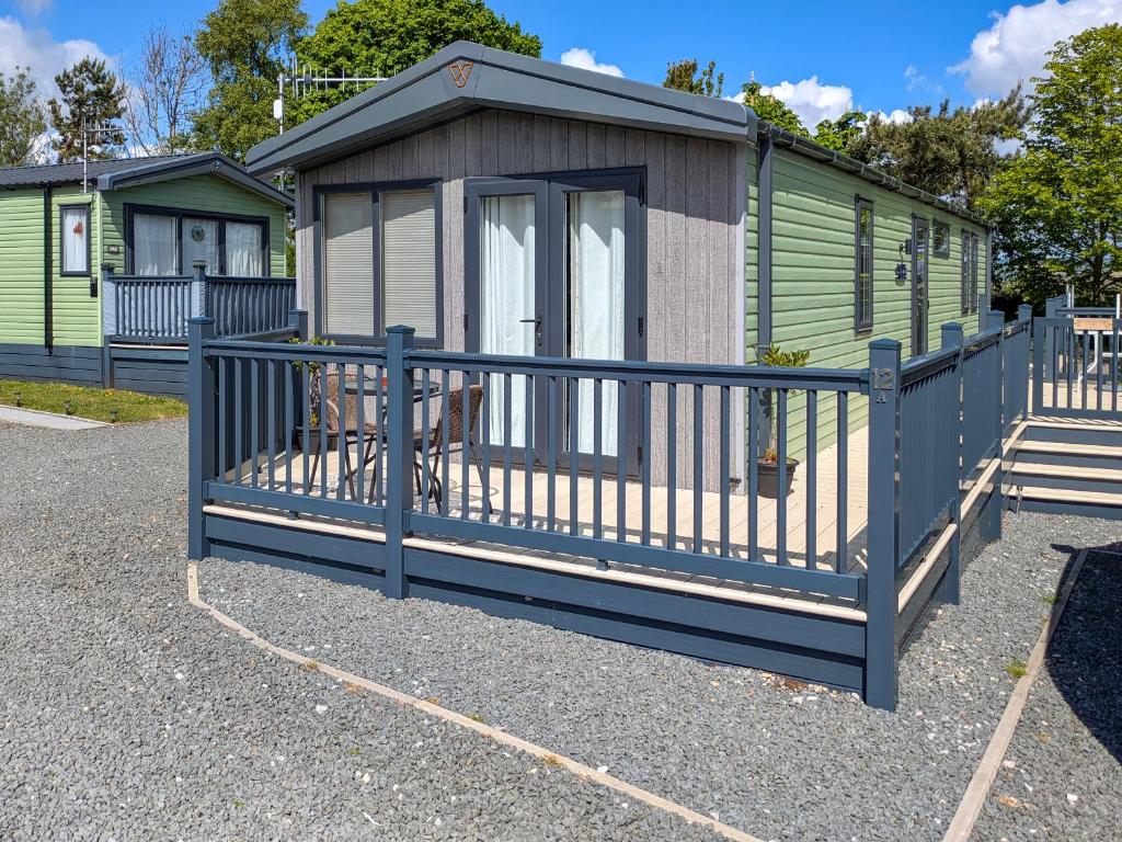 a small cabin with a blue fence in a parking lot at Solo's in East Heslerton