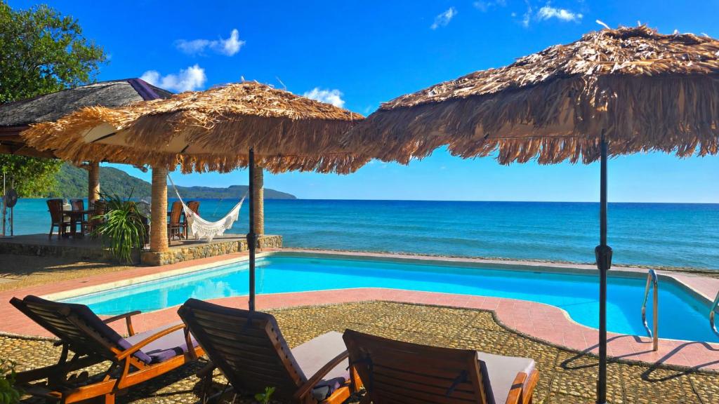 a resort with a swimming pool with chairs and umbrellas at Palmelía Beach Resort in Buruanga