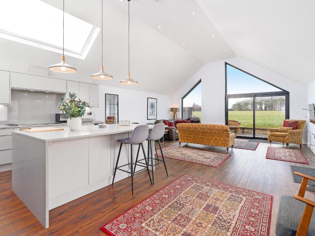 a kitchen and living room with a counter and chairs at Bimblebox Stable in Reepham