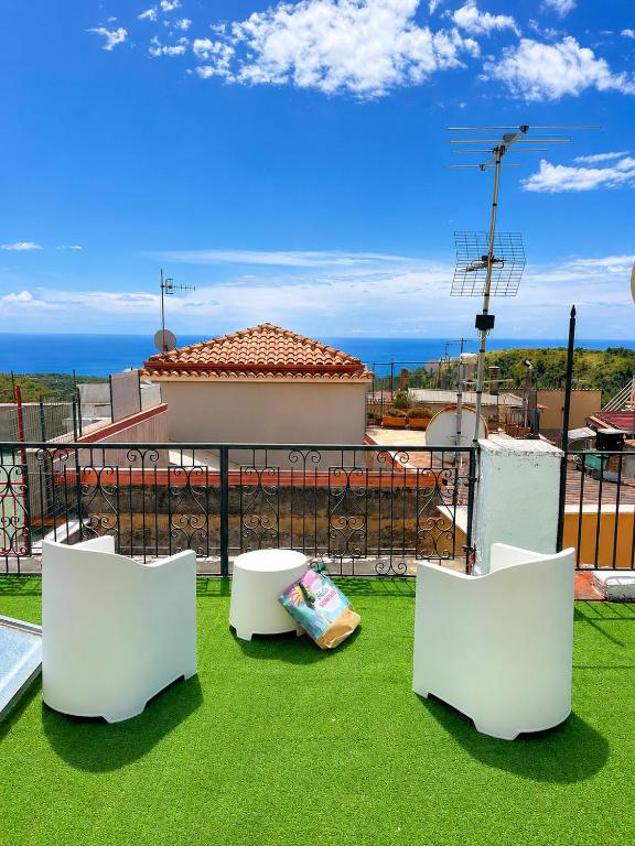 two white chairs sitting on the grass on a balcony at Terrazza sul Borgo in Camerota