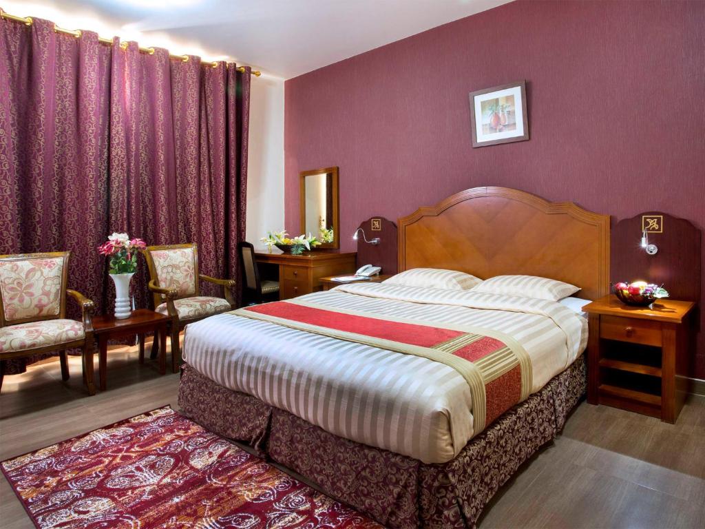 1 dormitorio con 1 cama grande y paredes moradas en Safeer Hotel Suites, en Mascate