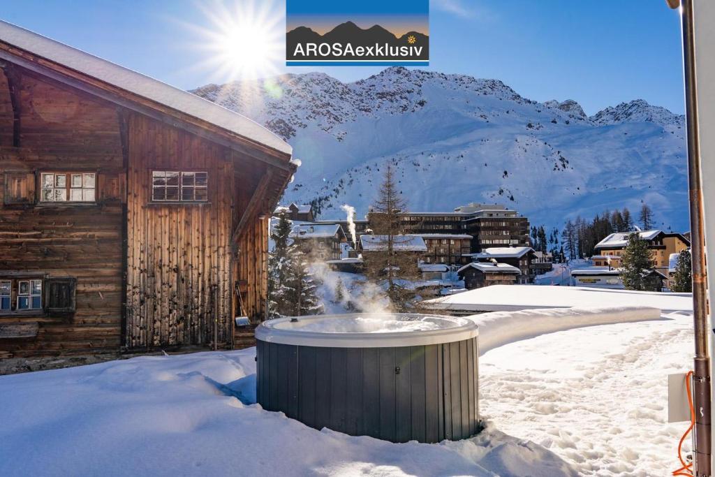 a snow covered building with a fountain in front of it at Alpslodge - Amelia in Arosa