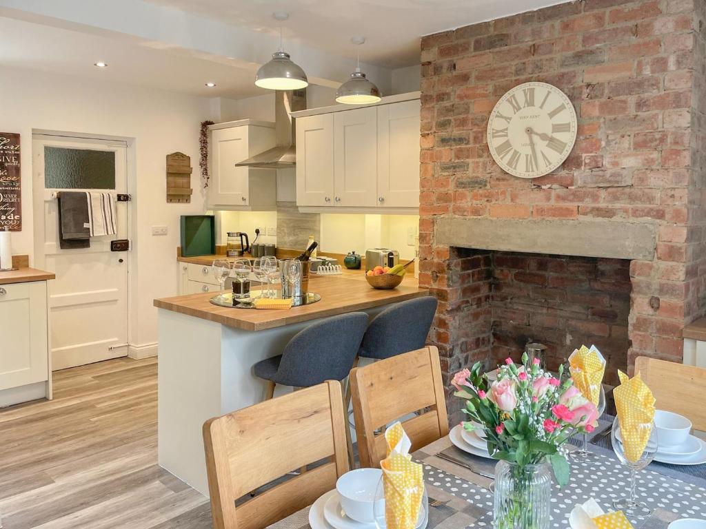 a kitchen and dining room with a brick fireplace at Mills Croft in Hognaston