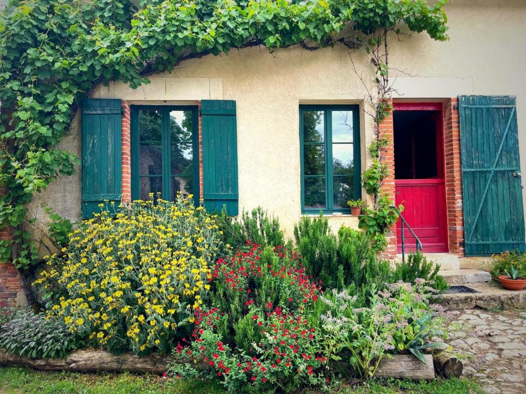 a house with a red door and some flowers at Ecurie Piaffe & Cie in Lurais
