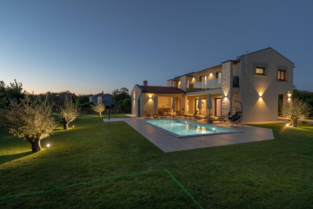 a house with a swimming pool in a yard at night at Casa Presika- Wellness, Fiber Net & Peace in Labin