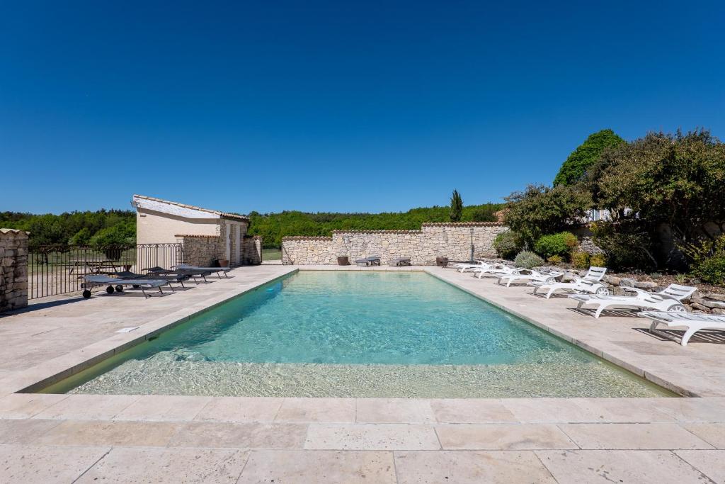 a swimming pool with chaises and chairs in a yard at La Grange D'anthounin in Redortiers
