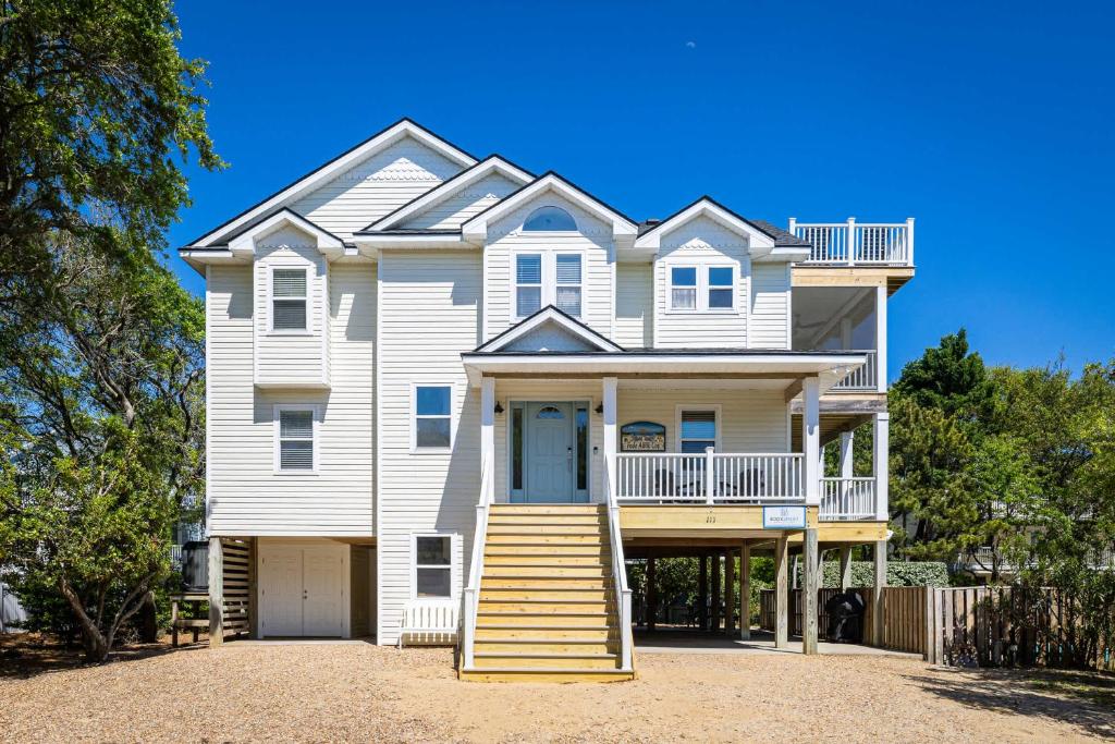 a large white house with a porch and stairs at Oceanside retreat with pool & spa June Weeks Open in Sanderling