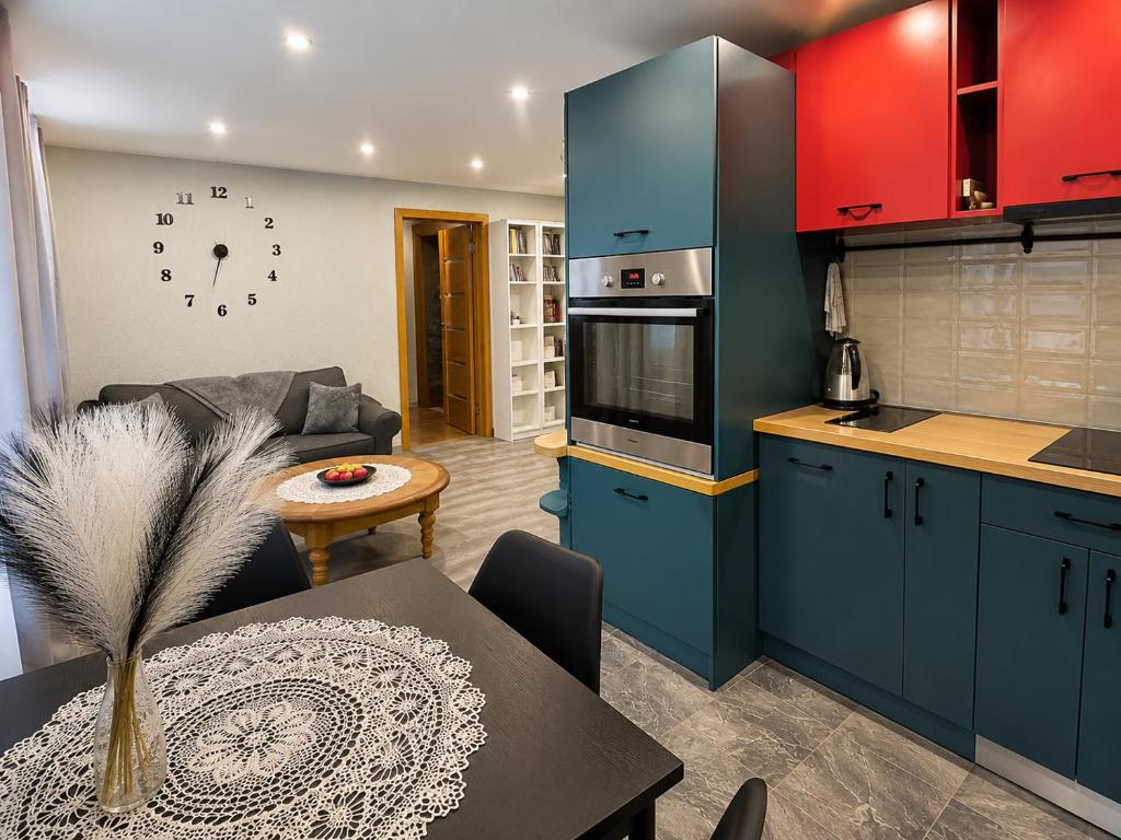 a kitchen and living room with blue cabinets and a table at Cimmele Apartment in Sigulda