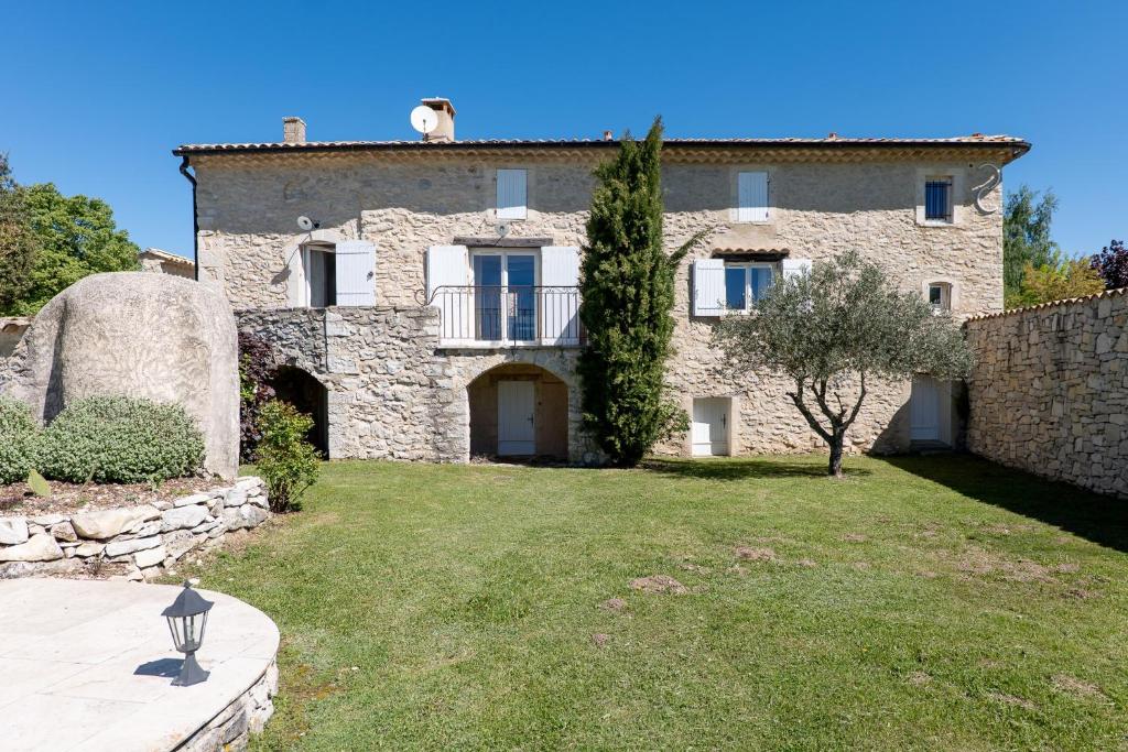 a large stone house with a grass yard at Bastide de Marius in Redortiers