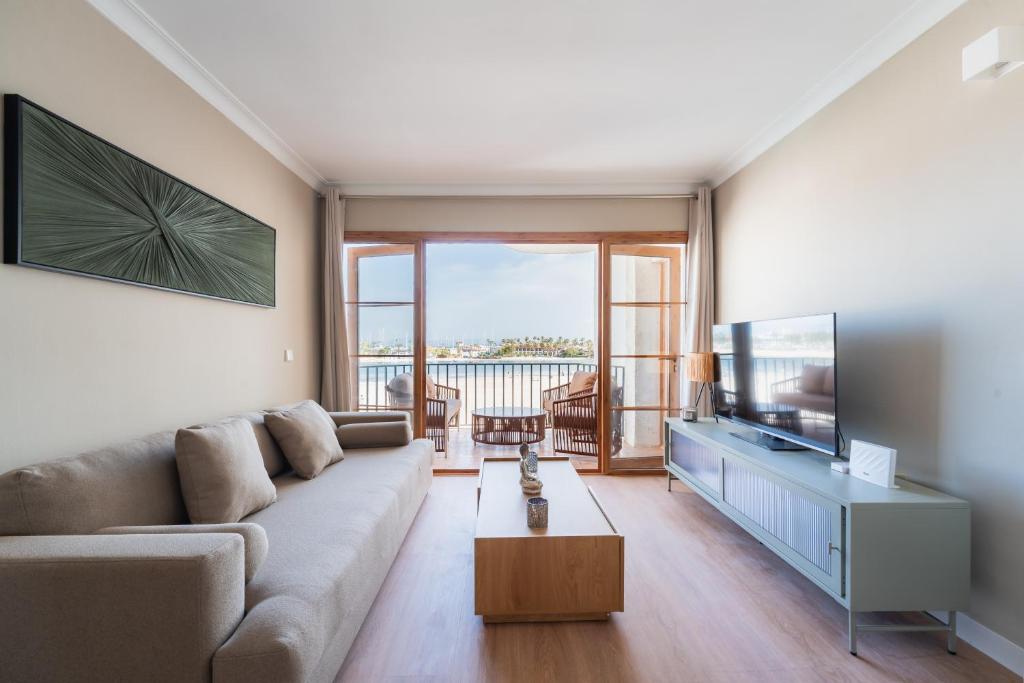 a living room with a couch and a flat screen tv at CARABELA 93 in Alcudia