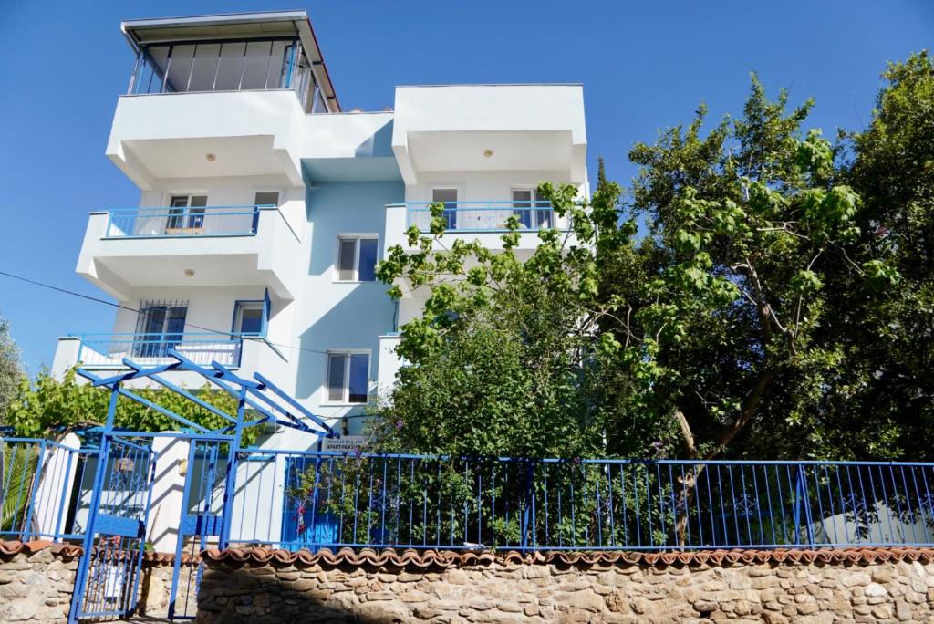 a white building with a blue fence in front of it at Domizil Lina Art in Güzelçamlı