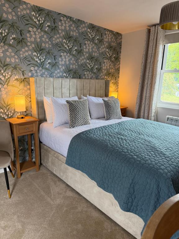 a bedroom with a large bed with a blue blanket at Little Fairfield in Ashover