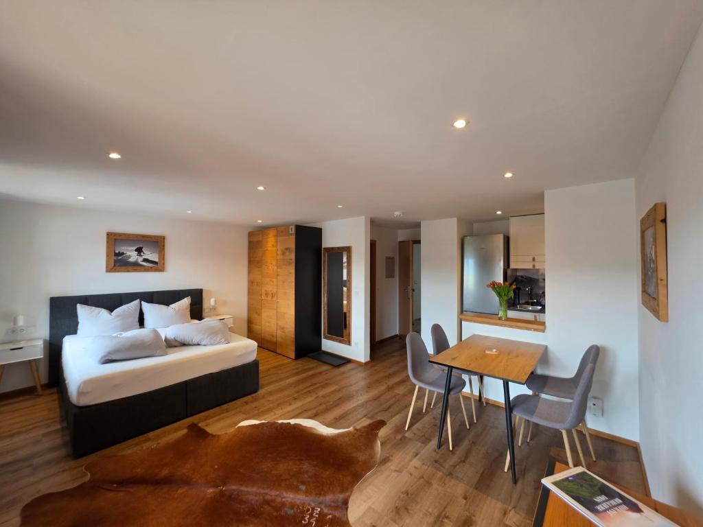 a bedroom with a bed and a table and chairs at Allgäuer Ferienwohnung mit Balkon, Bergblick und Wallbox in Rettenberg