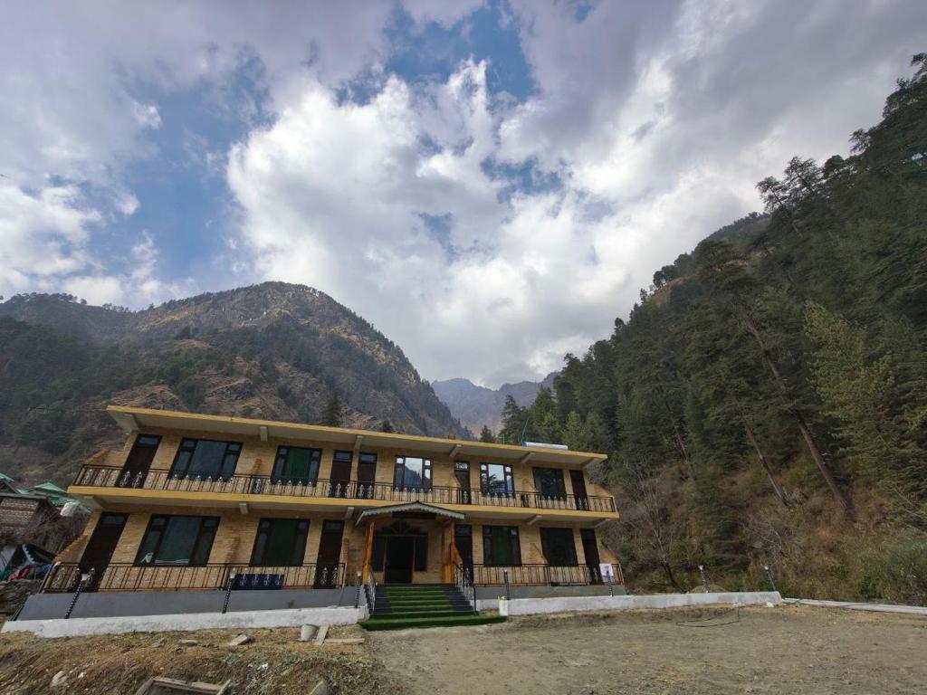 a building with a balcony and mountains in the background at Pratham Place in Kasol