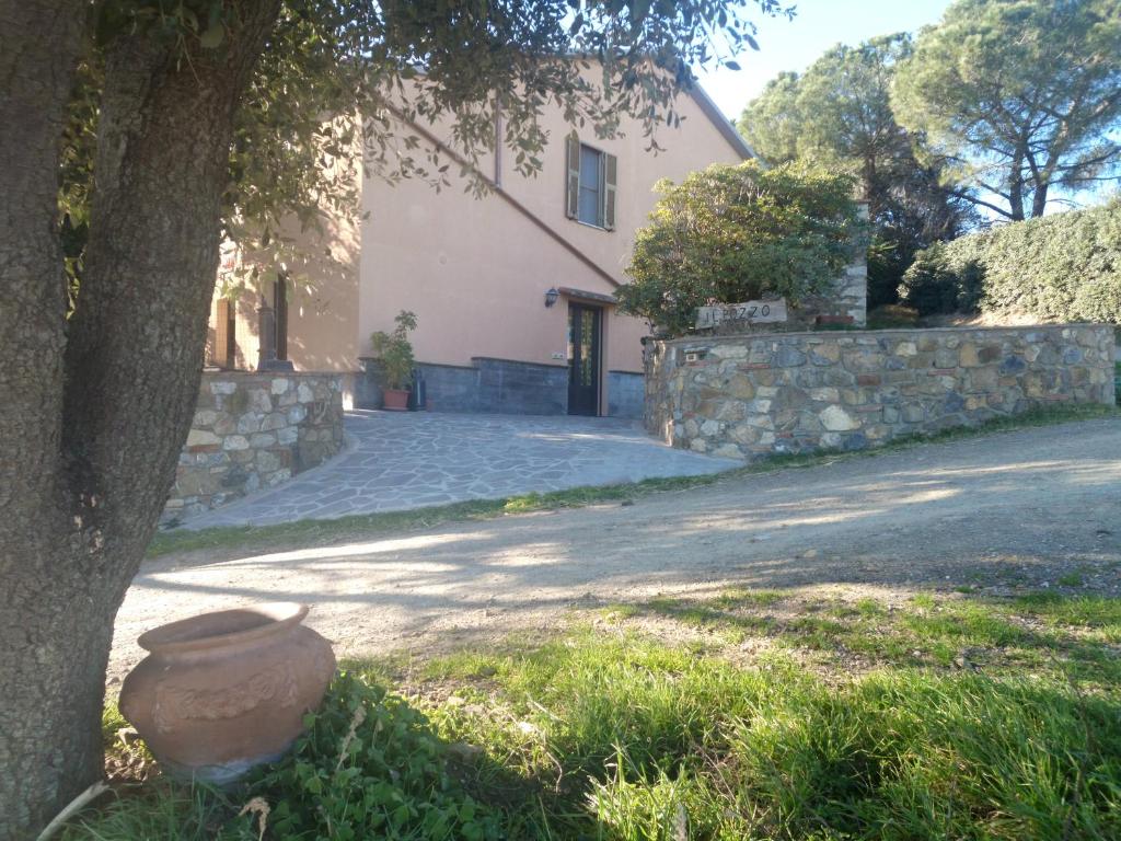 a house with a tree and a stone wall at Agriturismo il Pozzo in Campagnatico