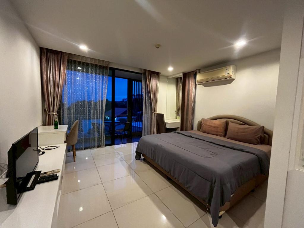 a bedroom with a bed and a desk and a television at The Pixel Sri Panwa, Phuket in Ban Ao Makham