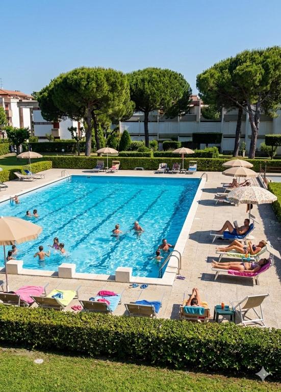a large swimming pool with people laying on chairs and umbrellas at Trilocale A2 in Marina di Bibbona