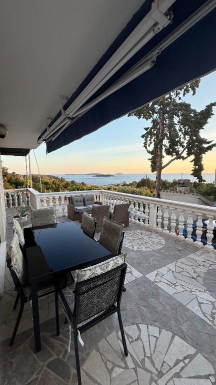 a patio with a table and chairs and a view of the ocean at Apartments Neda in Primošten