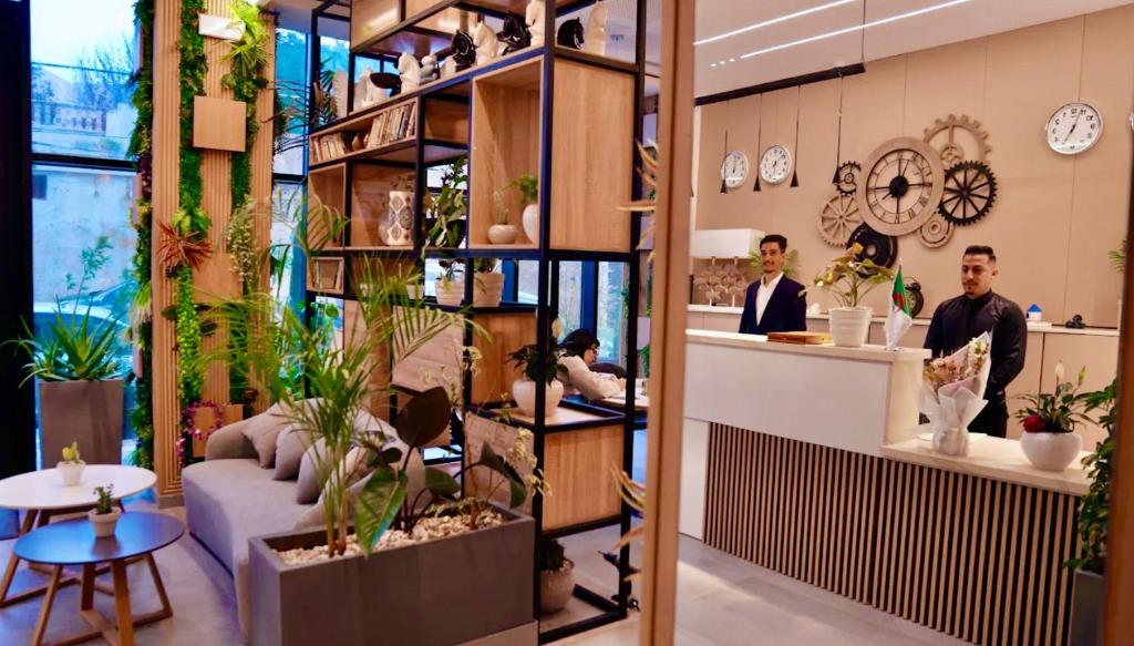 a lobby with people standing in a room with plants at Le Yot Hotel in 'Aïn Benian