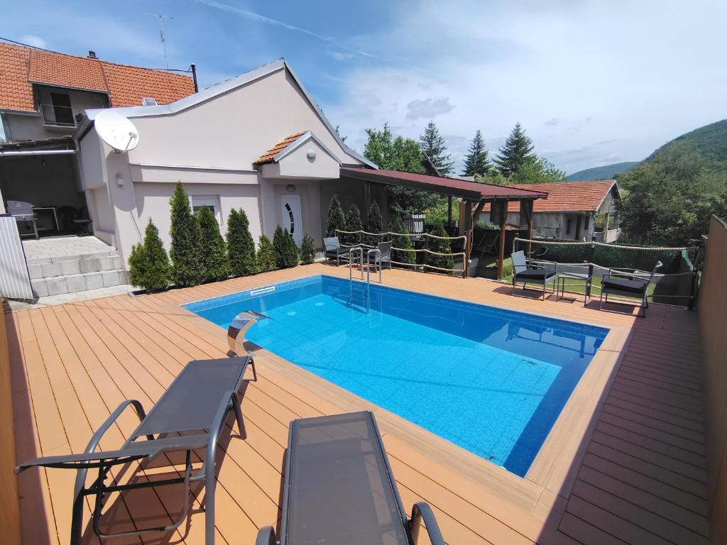 a swimming pool on a wooden deck next to a house at Vikendica sa bazenom"Mila"Banja Topilo in Banja Topilo