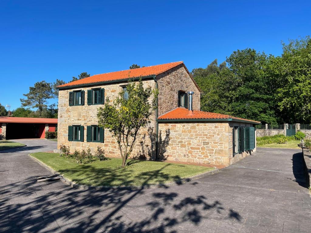 a brick building with an orange roof on a street at Casa Rural A Redondiña in Lamas