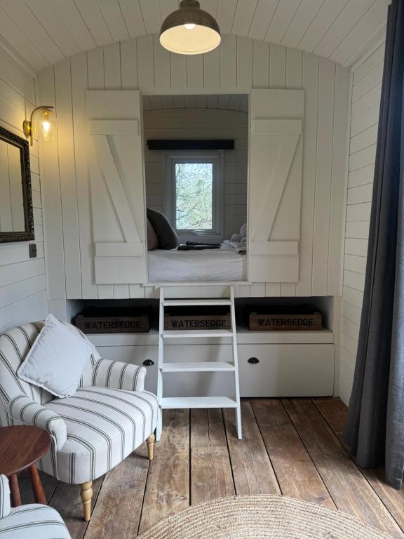 a room with a bed and a couch and a mirror at Lakeside Shepard's Hut 'Sanderling' in Bishampton