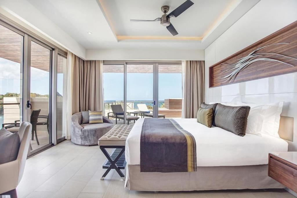 Bedroom with king bed, balcony access, lounge chair, and ocean view.
