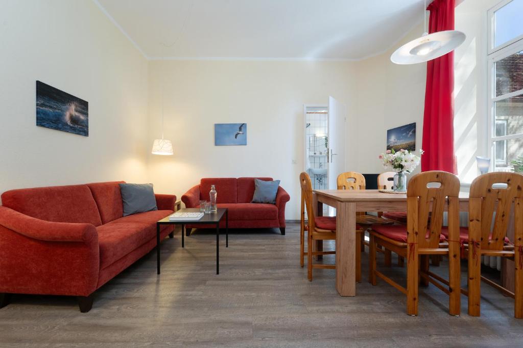 a living room with red chairs and a wooden table at Gut Staberhof Staberwind in Staberdorf