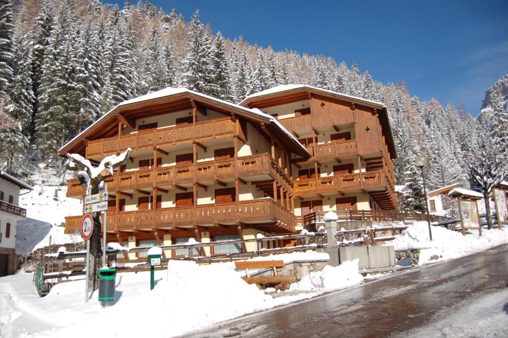a large wooden building in the snow with trees at Apartments Anny in Canazei