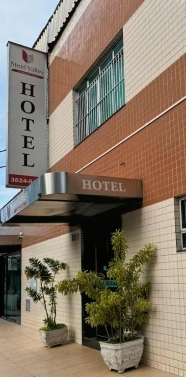 a hotel with two potted trees in front of it at Steel Valley Economic Hotel in Ipatinga