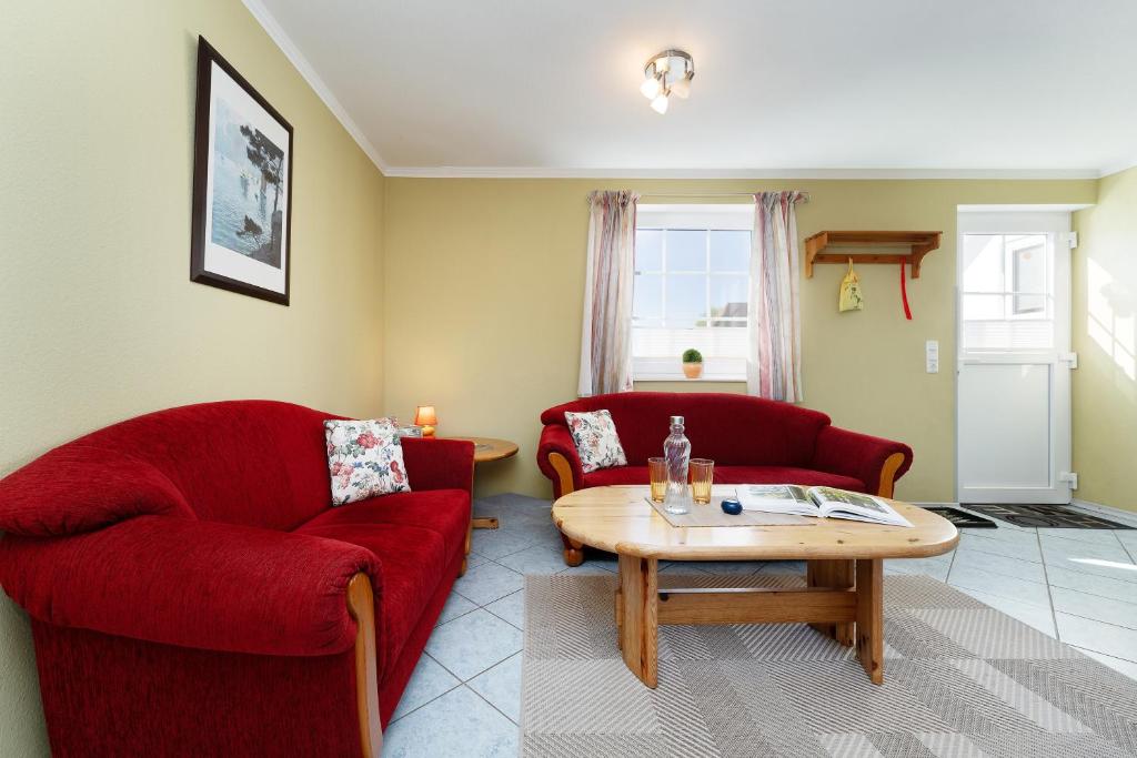 a living room with two red chairs and a coffee table at Dorfstraße 28 Seeadler in Klausdorf