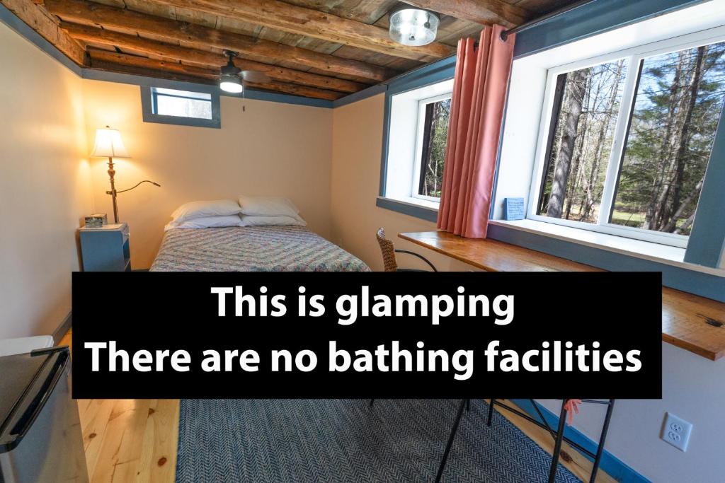 a bedroom with a bed and two windows at The ShackHilton at Dancing Light Farm in Bridgton