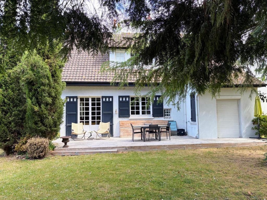 a house with a patio with a table and chairs at Maison de famille - Proche Centre Ville et Plage in Cabourg