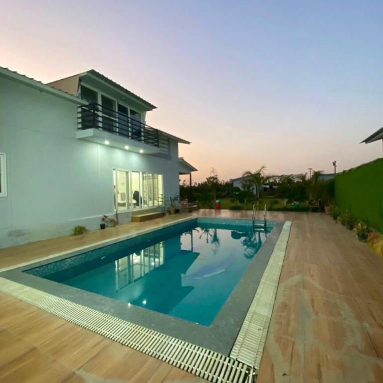 a swimming pool in front of a house at GoBravo 48 - 2BHK Farm with Pool and Garden Sector 150 Noida in Greater Noida