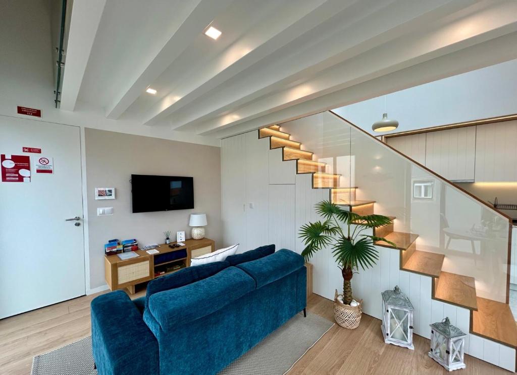 a living room with a blue couch and a staircase at The Charming Loft in Esposende