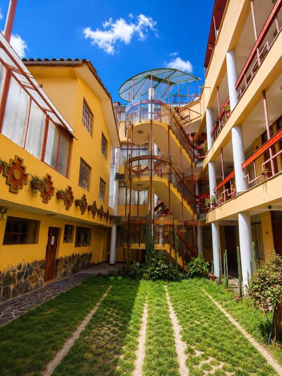 a large yellow building with a lawn in front of it at Killaqente in Cusco