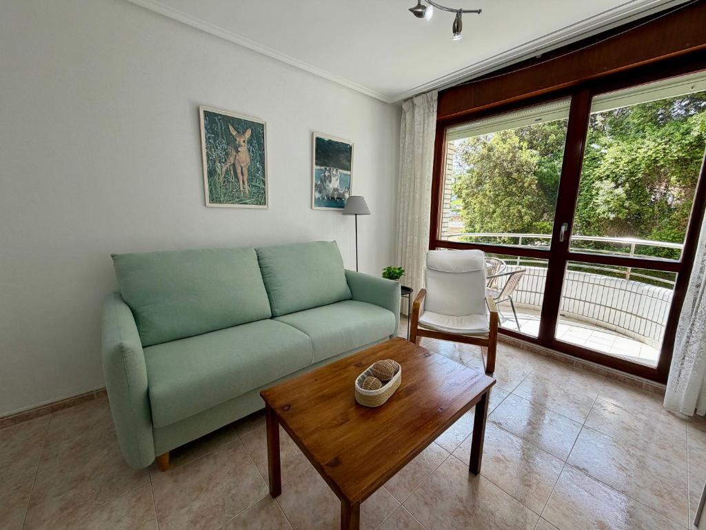 a living room with a green couch and a table at Apartamento Playa Azul - 5924 in Arnuero