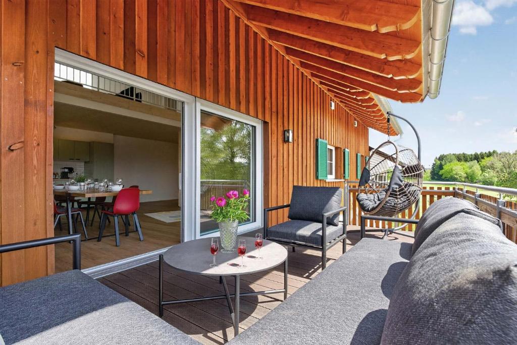 a patio with a couch and chairs and a table at FeWo Nägeleried - Große Galerie-Wohnung mit Balkon, Heimkino, Garten in Sulzberg