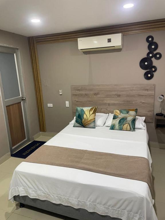 a bedroom with a large white bed and a fan at Hotel Santo Rio Suite Santa Marta in Santa Marta
