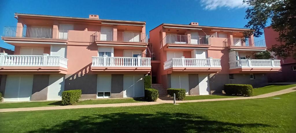a pink building with white balconies and a yard at Naturaleza y Golf in San Jorge