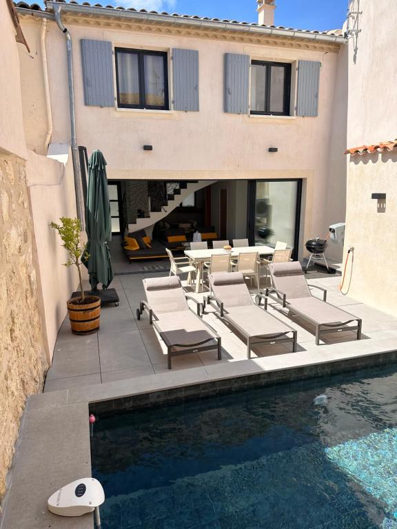 a patio with chairs and a pool in front of a building at La pointe au sel in Aigues-Mortes