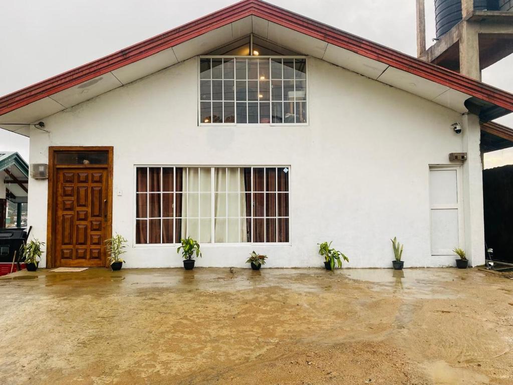 a white building with a door and potted plants at Infinity Winter Resort in Nuwara Eliya