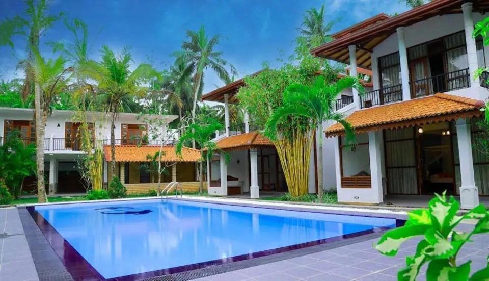 a villa with a swimming pool in front of a house at Villa Estuary in Bentota