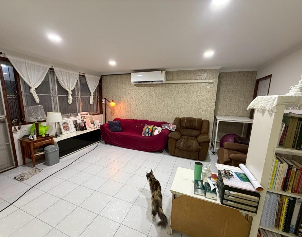 a living room with a red couch and a cat in it at Southeast Asia Activist House in Bangkok