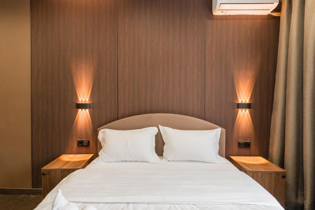 a bedroom with a bed with two lamps on it at MIRAFI Hotel in Almaty