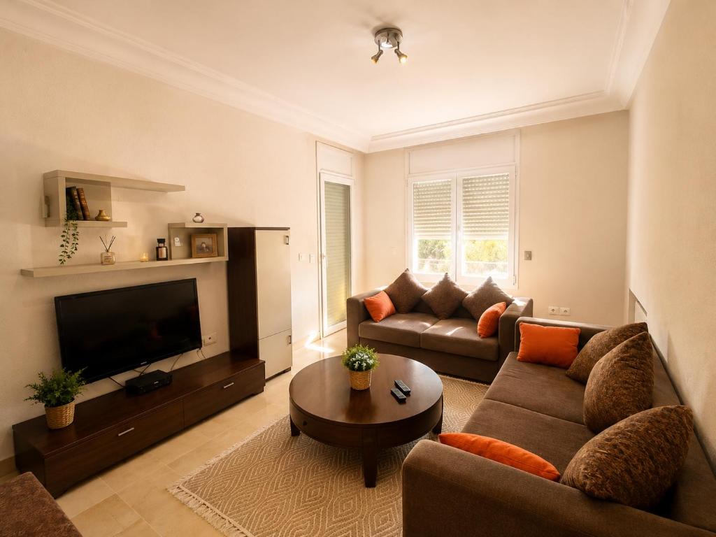 a living room with a couch and a television at Cozy Stay appartement in Sukrah