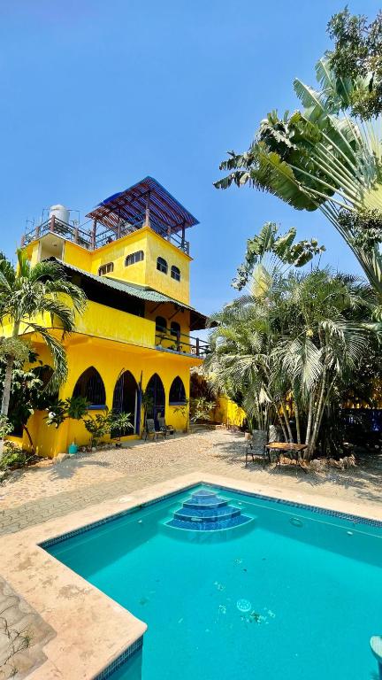 a yellow building with a swimming pool in front of it at Casa Colibri La Punta in Brisas de Zicatela