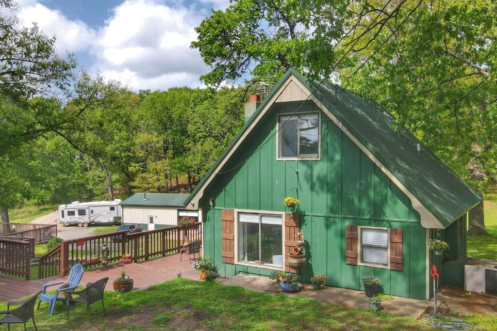 a green house with a deck in front of it at Lakefront Cabin: Boat Dock, Pool & Hot Tub in Grove