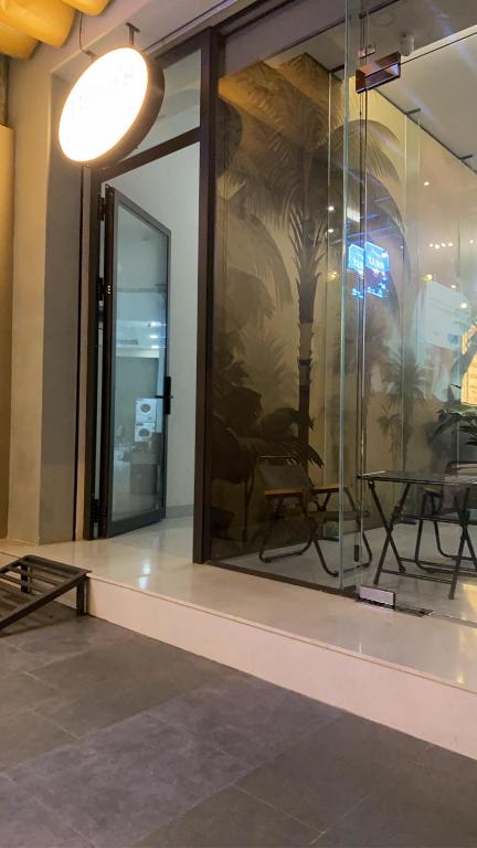 a room with a glass wall with a table and chairs at Bống's Homestay and Cafe in Ho Chi Minh City